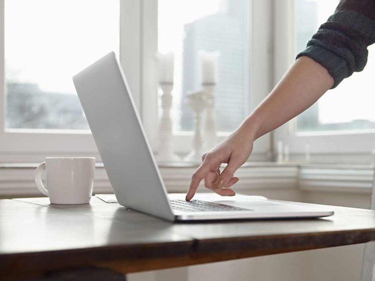  Eine Frau tippt mit dem Zeigefinger auf die Tastatur eines Laptops