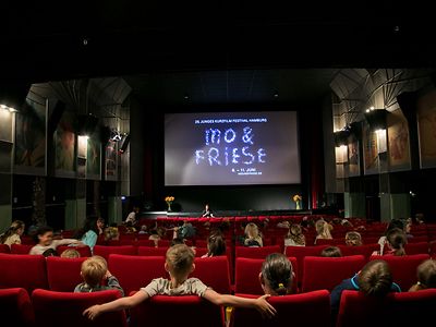  Kinder sitzen im Rahmen des Mo&Friese in einem Kinosaal und sehen sich einen Kurzfilm an.